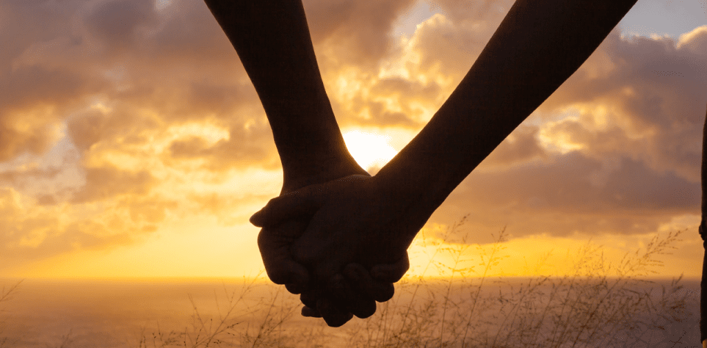 Two people holding hands at sunset